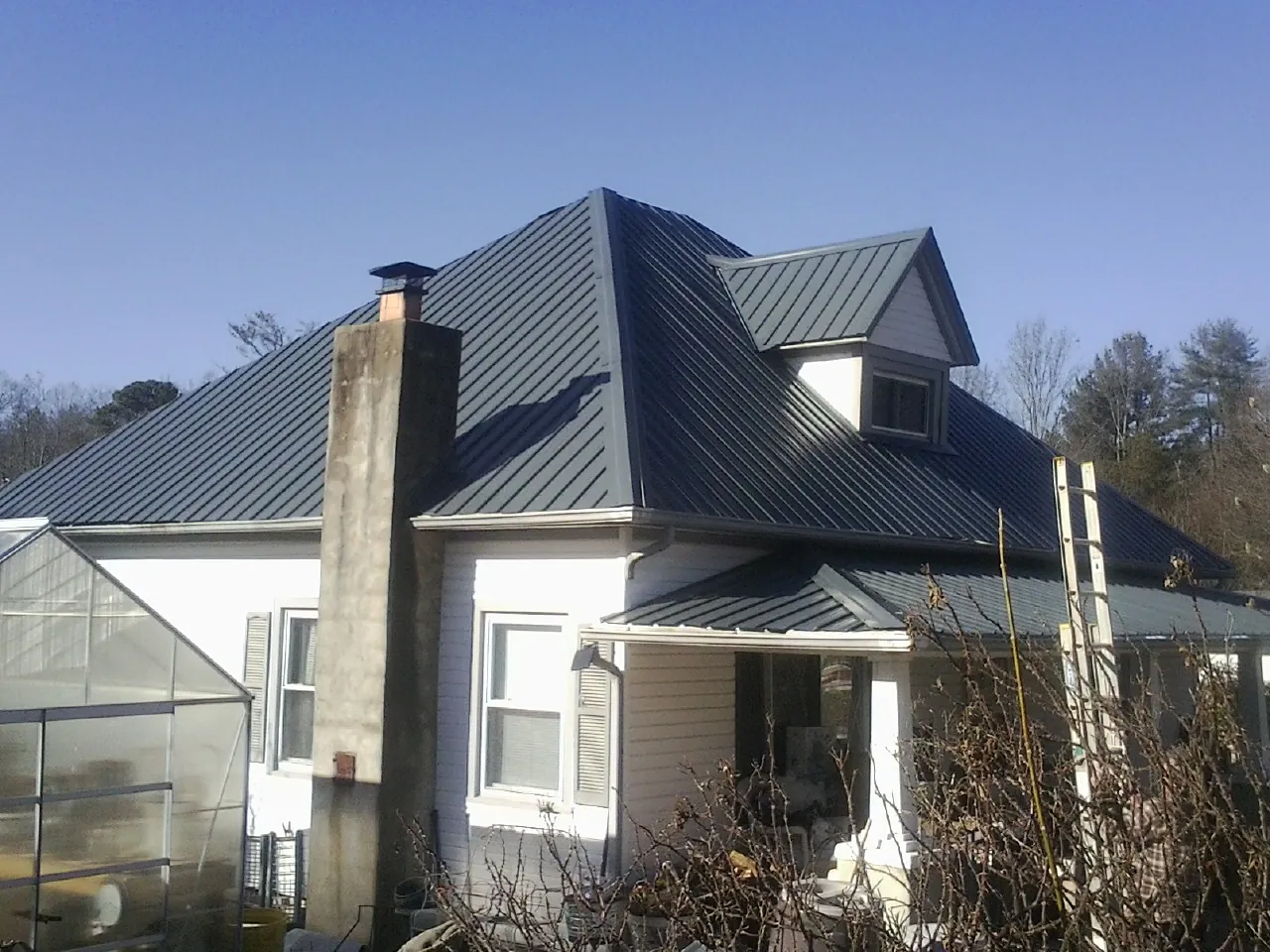 Dark blue standing seam metal roof on a white farmhouse with dormer — Slate & Tile Roof Repair by Roofing Brothers in Totowa