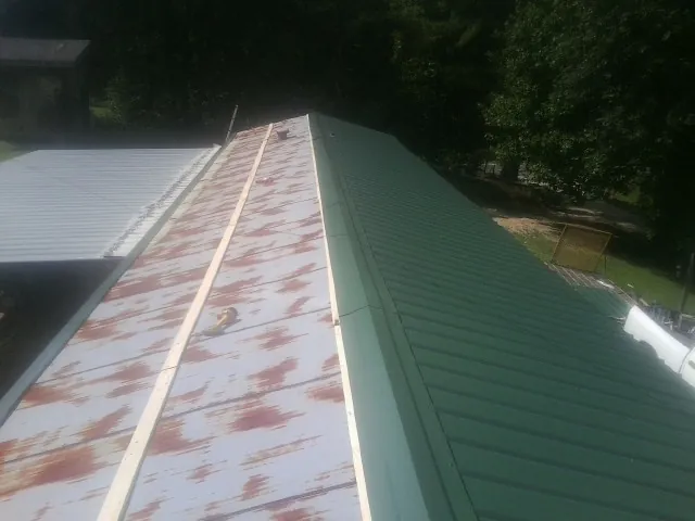 Old rusted panels beside newly installed green metal roofing — Wind Damage Roof Repair by Roofing Brothers in Totowa
