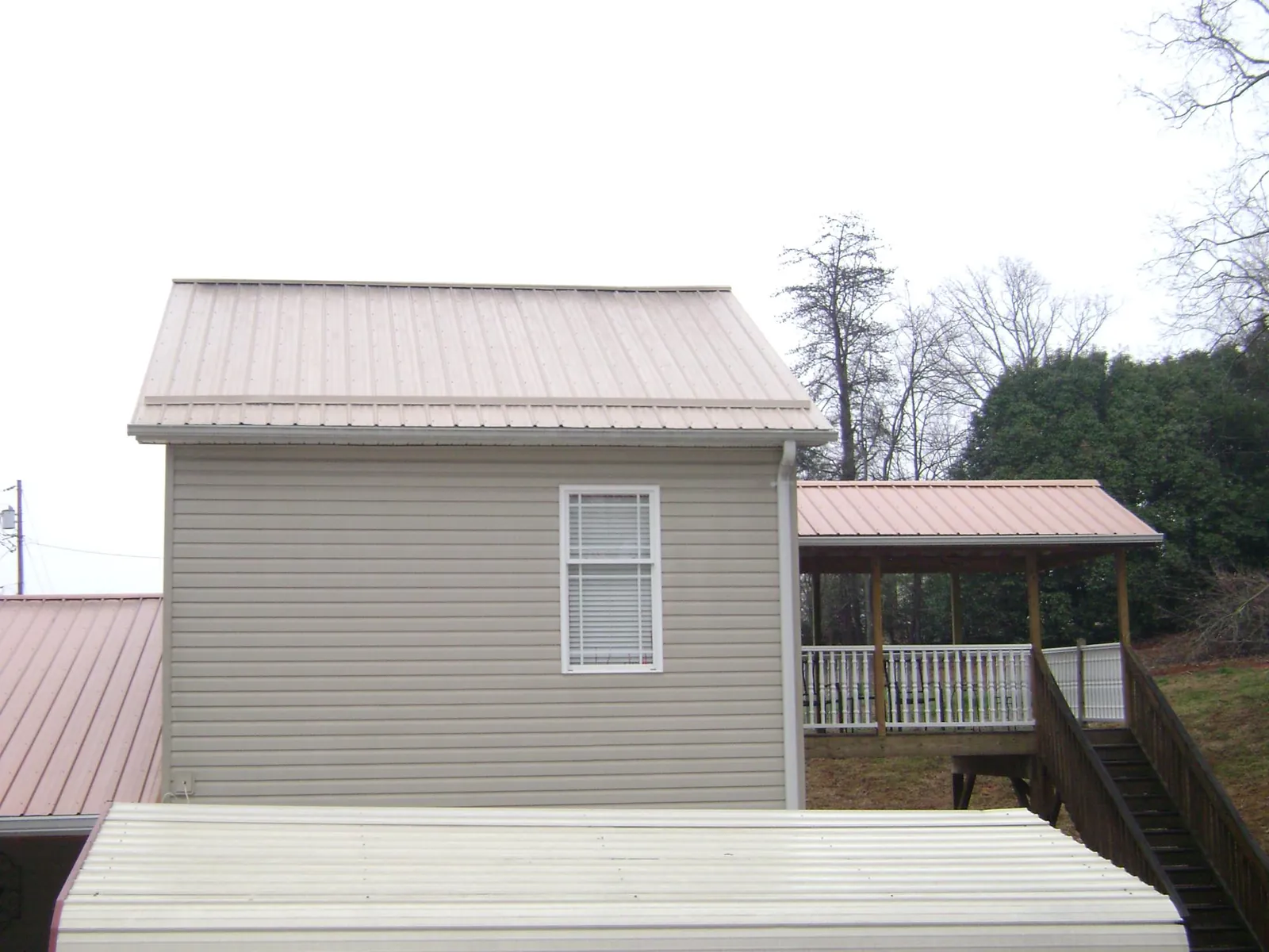 Tan metal roofs on a two story addition and attached porch, from a Roof Replacement job in Totowa