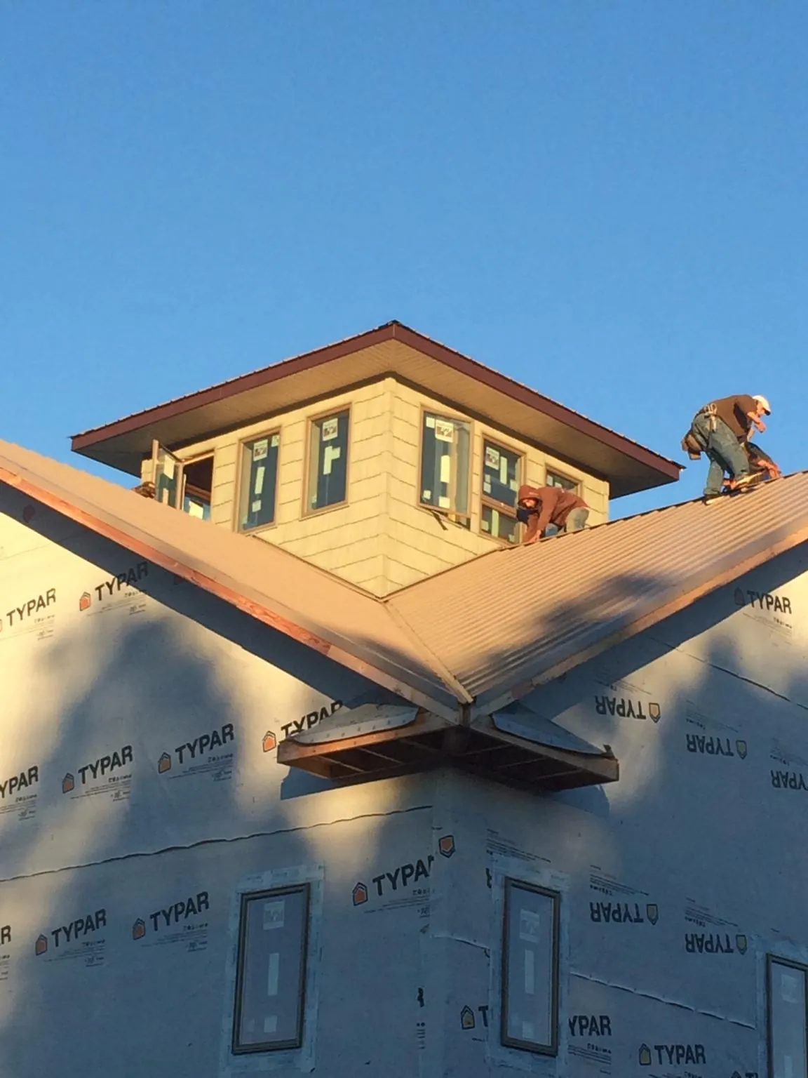 Roofers working around a rooftop cupola on a new metal roof at sunset — Roof Waterproofing in Totowa by Roofing Brothers